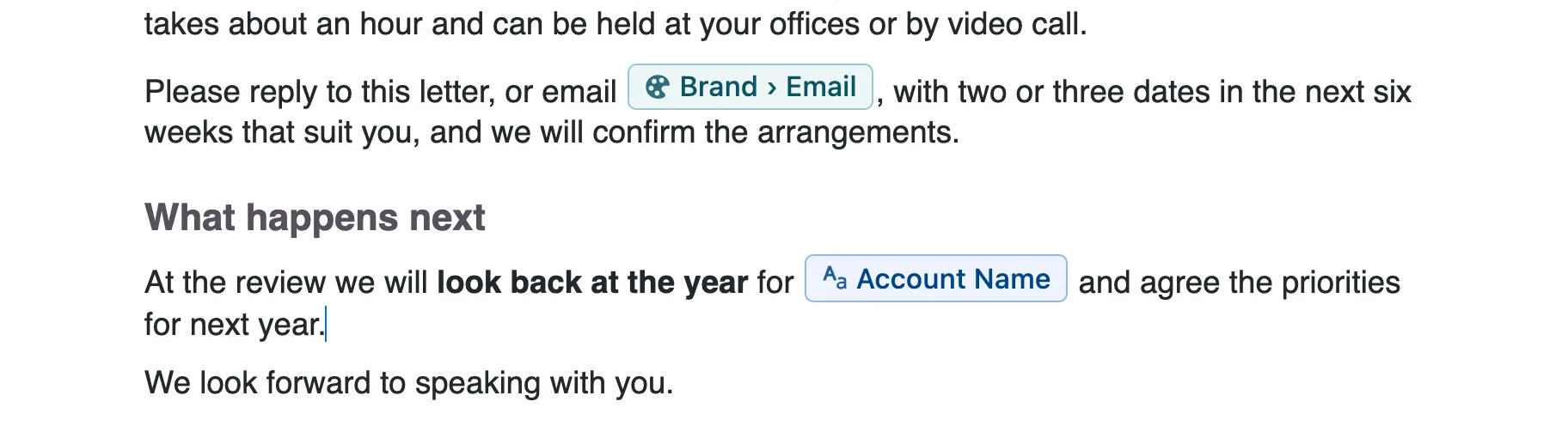 A close-up of a letter being typed in the Docable editor: a sentence with a Brand Email chip in it, a heading What happens next, and the sentence At the review we will look back at the year for, an Account Name chip, and agree the priorities for next year, with the cursor at its end.
